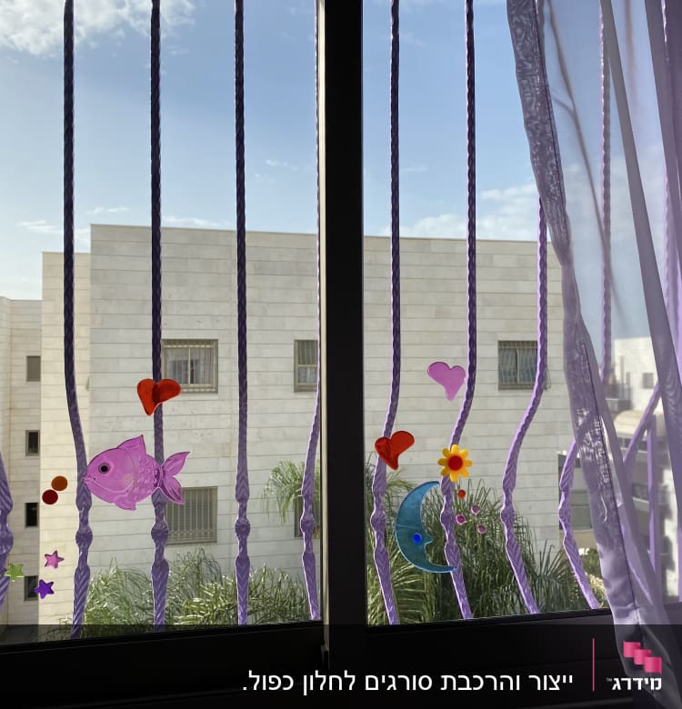 מדבקות צבעוניות על סורגי חלון עם וילון סגול